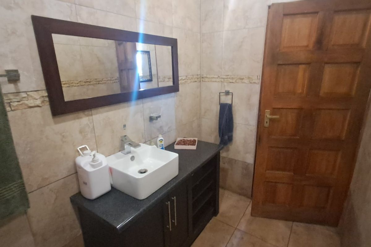 A functional bathroom featuring a modern vessel sink on a dark vanity cabinet, complemented by neutral wall tiling and a solid timber door.