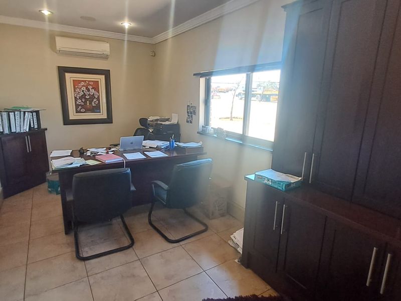 A functional office space featuring tiled flooring, built-in cabinetry for storage, and a wall-mounted air conditioning unit.