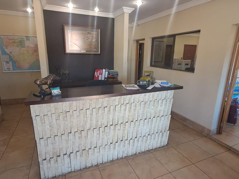 A professional reception area featuring a stone-clad desk, ceramic tile flooring, and recessed lighting, providing a functional entry point for the industrial property.