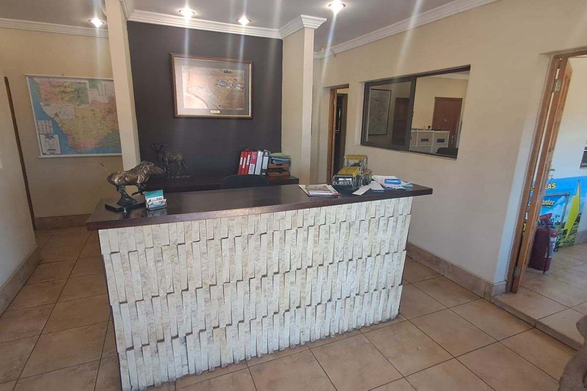 A professional reception area featuring a stone-clad desk, ceramic tile flooring, and recessed lighting, providing a functional entry point for the industrial property.