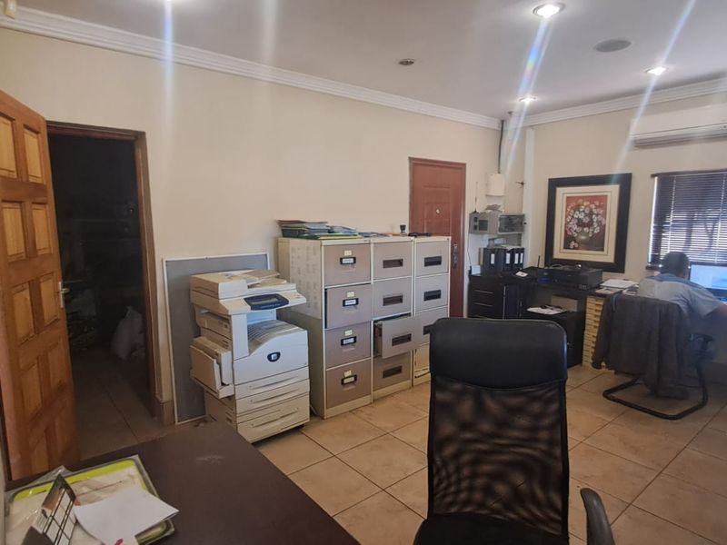 A functional office space featuring tiled flooring, recessed lighting, and an integrated air conditioning unit, suitable for professional use.