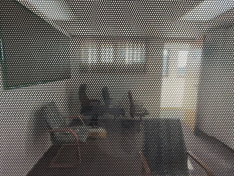 An office space viewed through a perforated privacy film, obscuring clear visibility of the room's features and condition.