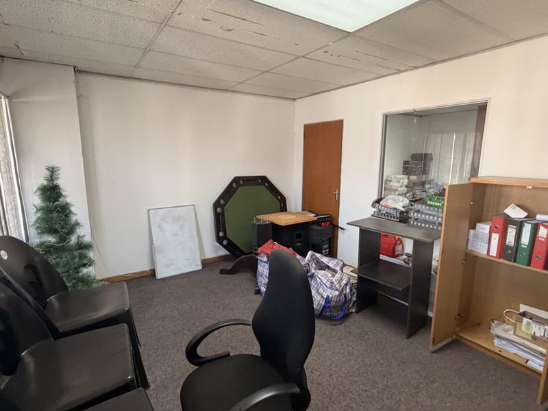 A dated office space featuring a suspended ceiling, carpet flooring, and an internal glass partition, suitable for renovation or modernization.
