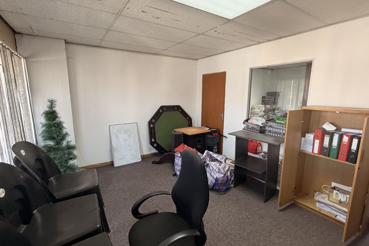 A dated office space featuring a suspended ceiling, carpet flooring, and an internal glass partition, suitable for renovation or modernization.