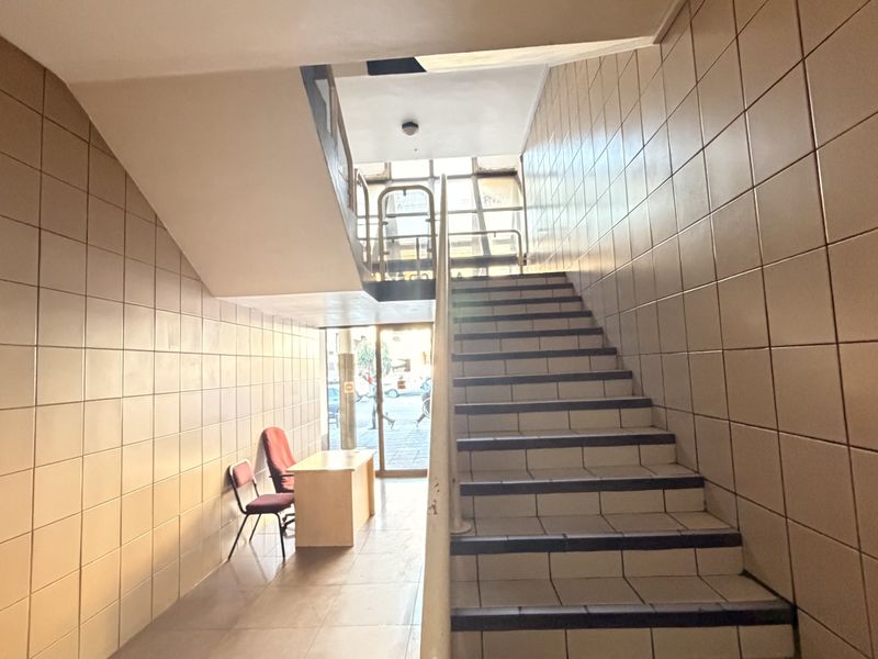 Entrance lobby featuring tiled walls and flooring with a central staircase leading to upper levels, providing access to the office building.