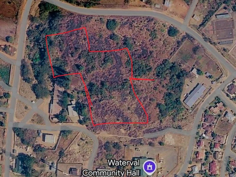Aerial view of a vacant commercial land plot with red boundary lines indicating the property perimeter.