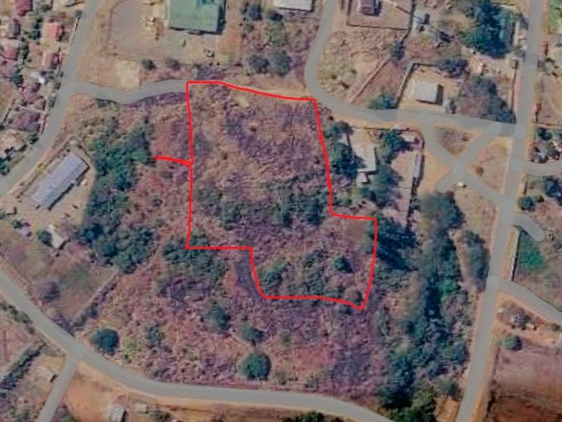 Aerial view of a vacant commercial land plot with red boundary lines indicating the property perimeter.