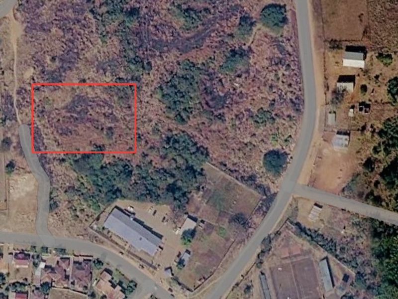 Aerial view of a vacant commercial land plot with road access, highlighting the undeveloped site boundaries.