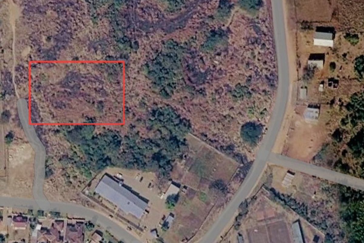 Aerial view of a vacant commercial land plot with road access, highlighting the undeveloped site boundaries.