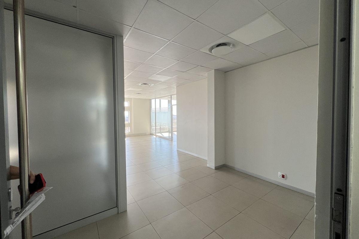 A bright, vacant office space featuring a suspended ceiling, tiled flooring, and glass partitions, offering a clean and professional environment.