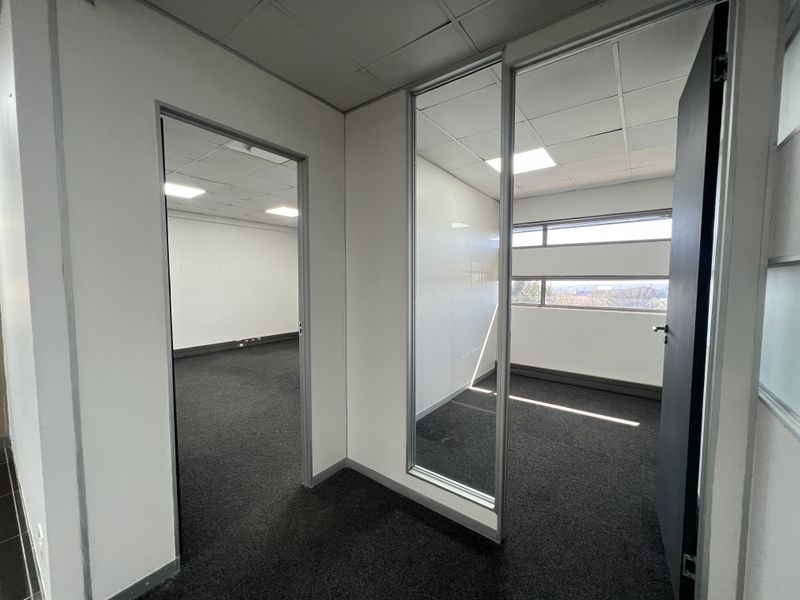 Empty office space featuring carpet flooring, suspended ceilings with recessed lighting, and a glass partition wall providing a bright, professional work environment.