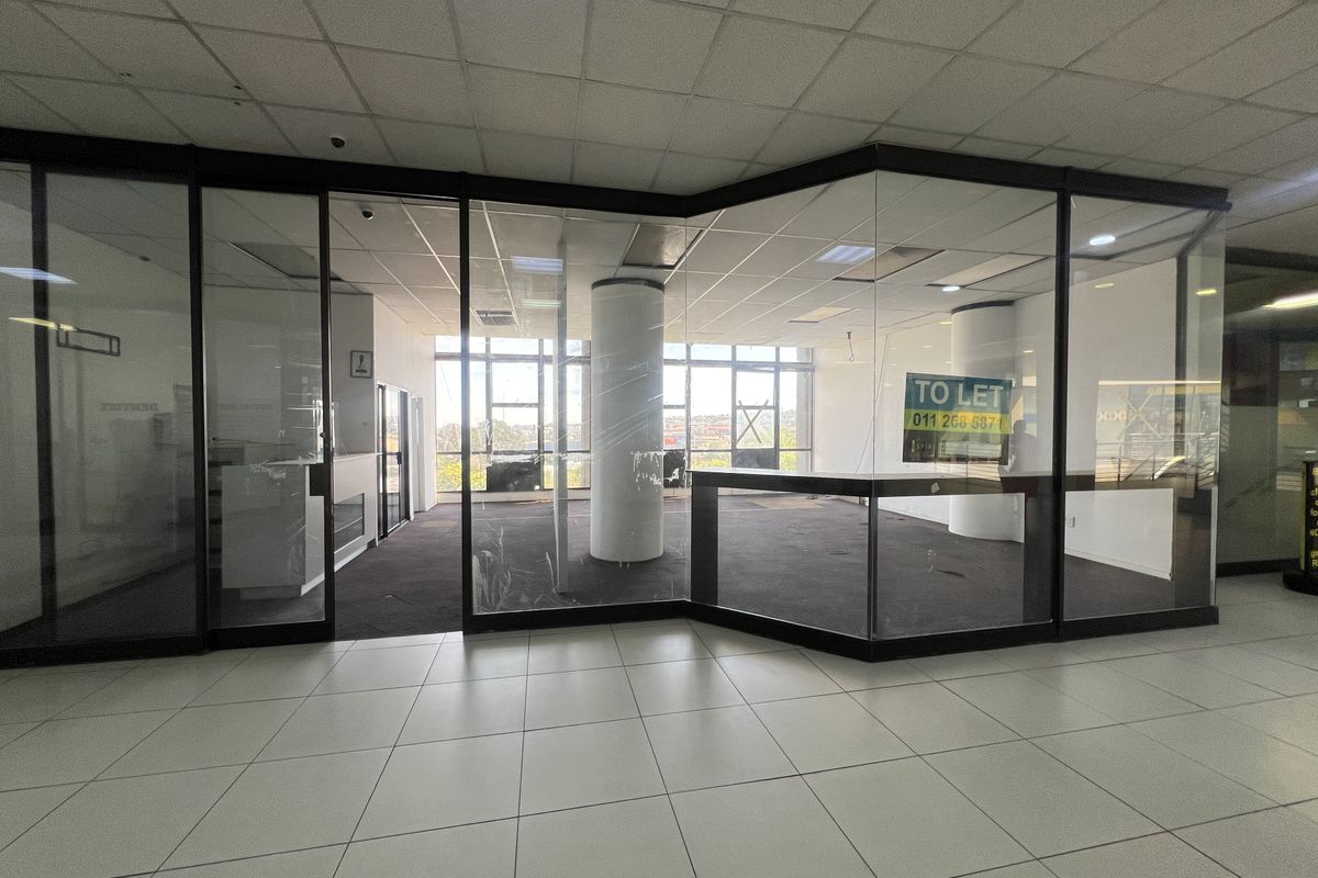 An open-plan commercial retail space featuring glass partitioning, suspended ceilings, and large windows, currently vacant and available for lease.