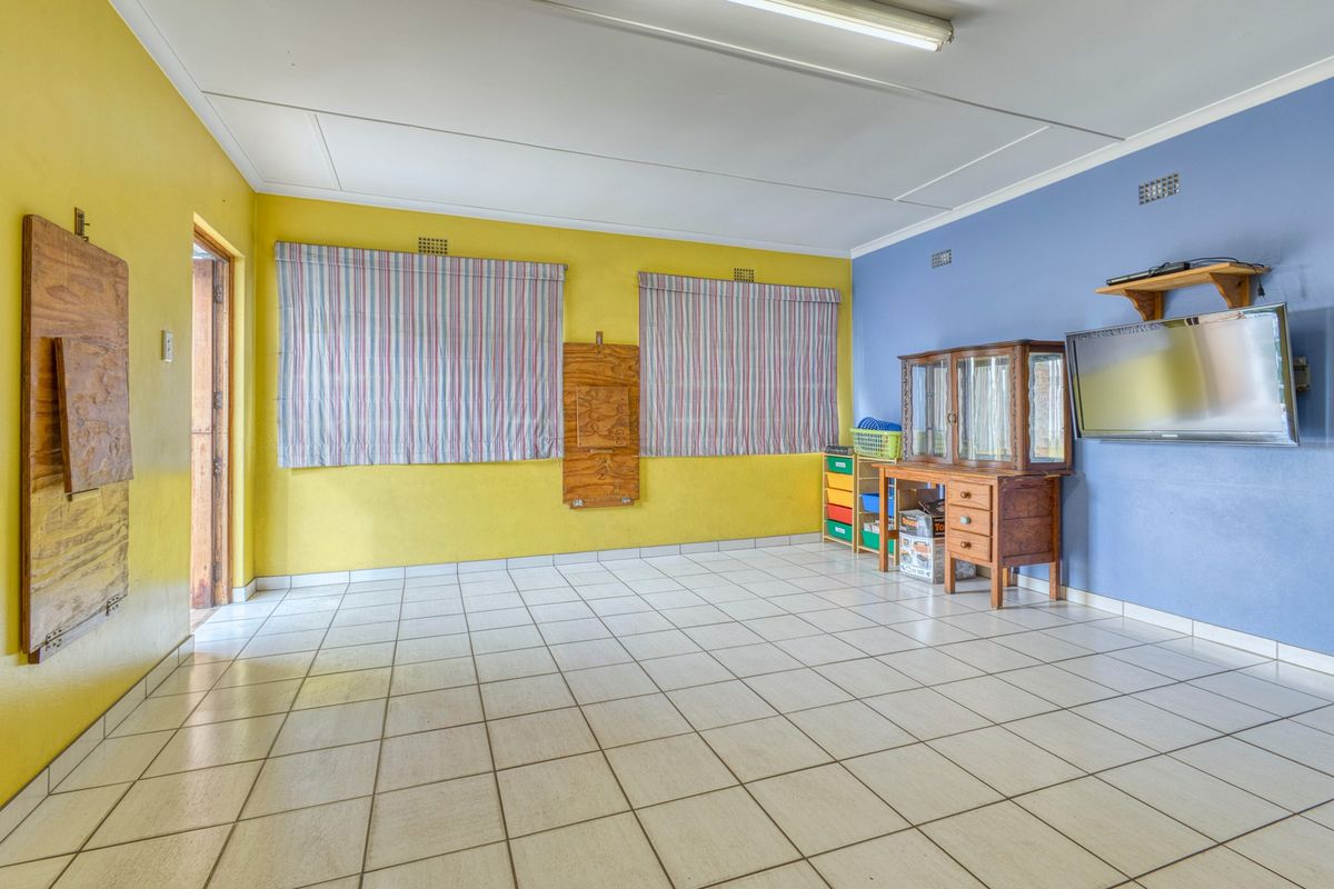 A spacious living area featuring ceramic tiled flooring, bright dual-tone wall finishes, and functional overhead lighting.