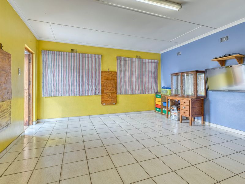 A spacious living area featuring ceramic tiled flooring, bright dual-tone wall finishes, and functional overhead lighting.