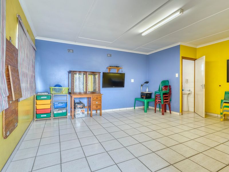 A multi-purpose utility space featuring tiled flooring, bright wall finishes, and an integrated pedestal sink, suitable for various commercial or office applications.