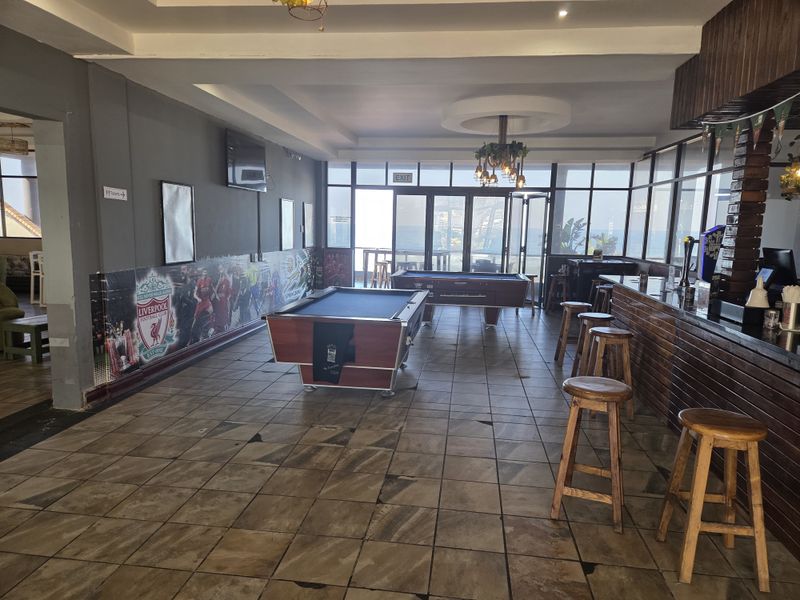 Spacious bar area featuring tiled flooring, a built-in service counter, and large glass doors providing natural light and access to the exterior.