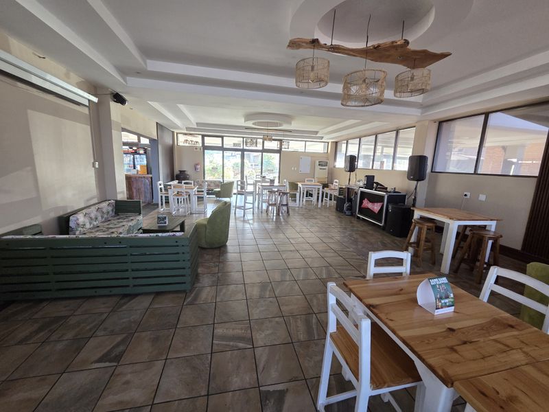 Spacious open-plan restaurant dining area featuring tiled flooring, recessed ceiling details, and large windows providing ample natural light.
