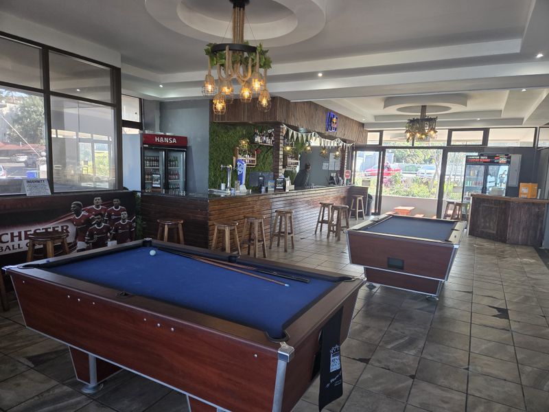 Spacious bar area featuring a built-in counter, tiled flooring, and large windows providing ample natural light and outdoor views.