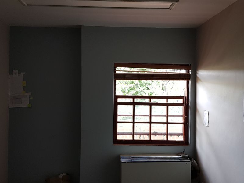 A vacant office space featuring a timber sash window, built-in HVAC unit, and recessed ceiling lighting.