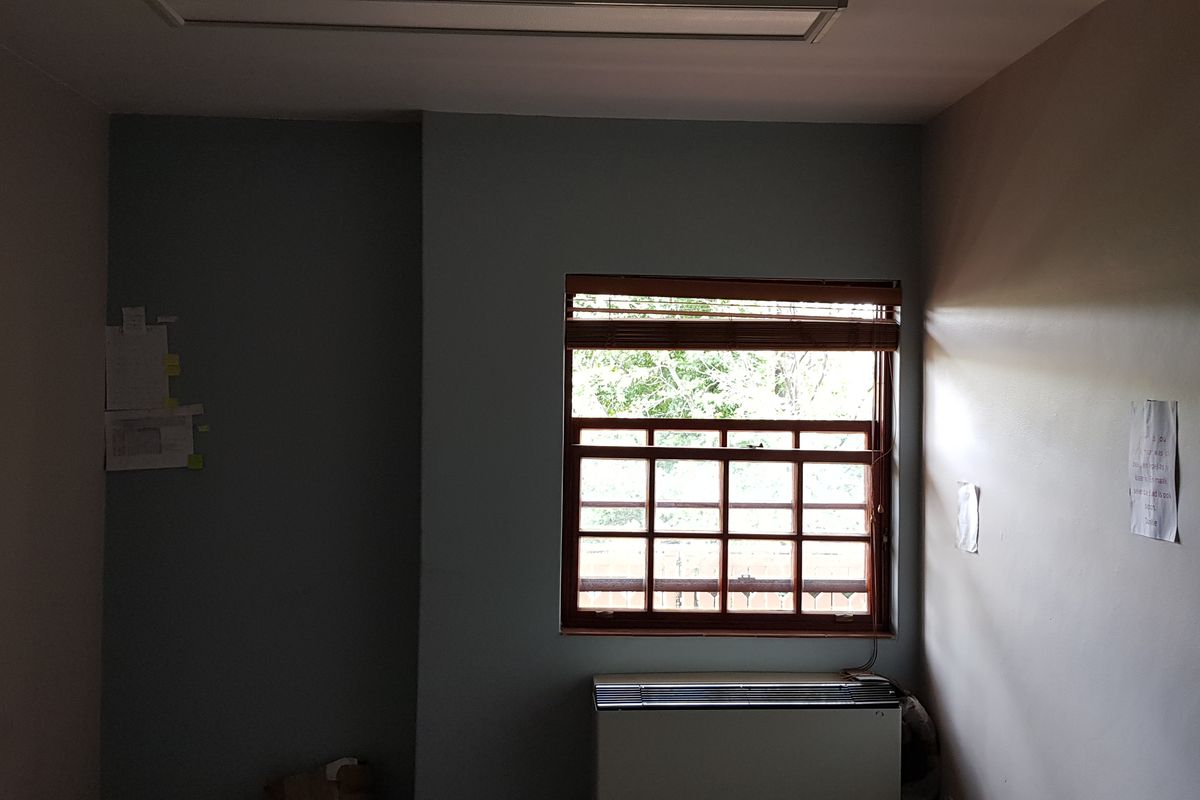 A vacant office space featuring a timber sash window, built-in HVAC unit, and recessed ceiling lighting.