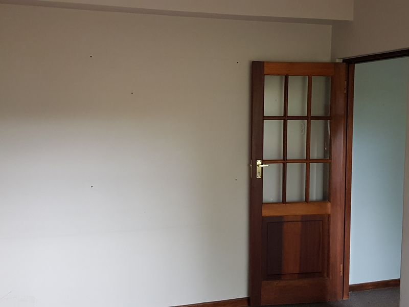 An empty office space featuring a classic timber-framed glass door and neutral wall finishes.