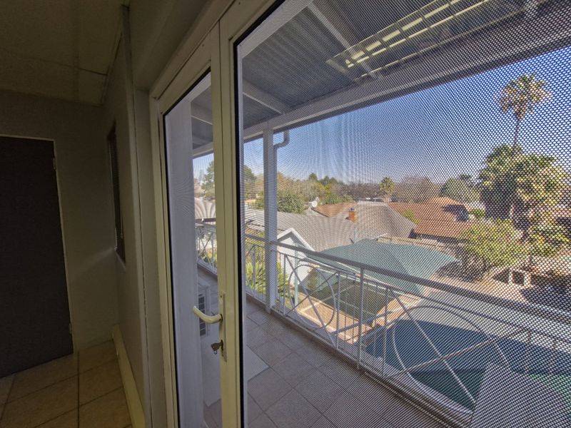 A covered balcony featuring tiled flooring and a metal balustrade, offering an elevated view of the surrounding residential area.