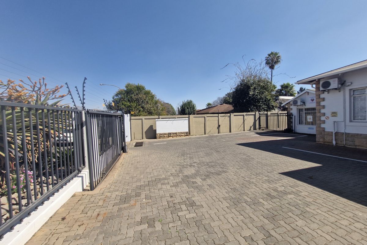 Exterior view of the office property featuring a paved driveway, secure perimeter wall with electric fencing, and a sliding gate entrance.