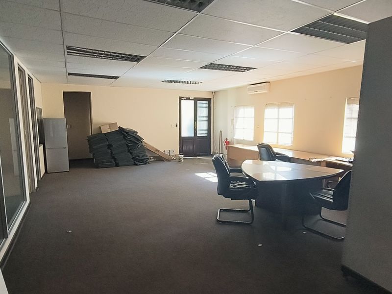Spacious office area featuring a suspended ceiling, recessed lighting, air conditioning, and glass partitioning, offering a functional workspace with carpeted flooring.