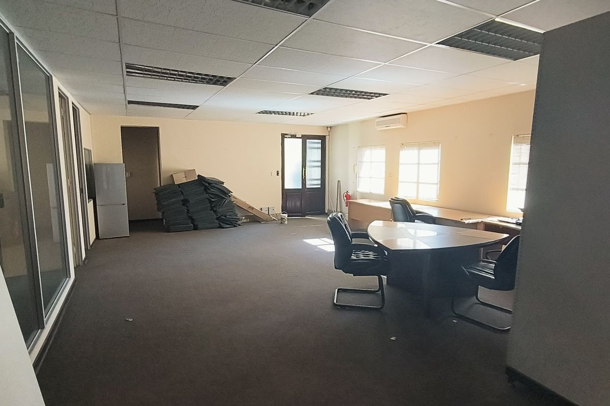 Spacious office area featuring a suspended ceiling, recessed lighting, air conditioning, and glass partitioning, offering a functional workspace with carpeted flooring.