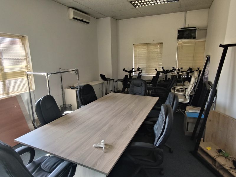 A functional office space featuring a suspended ceiling, split-system air conditioning, and multiple windows with venetian blinds, suitable for a professional meeting or workspace.