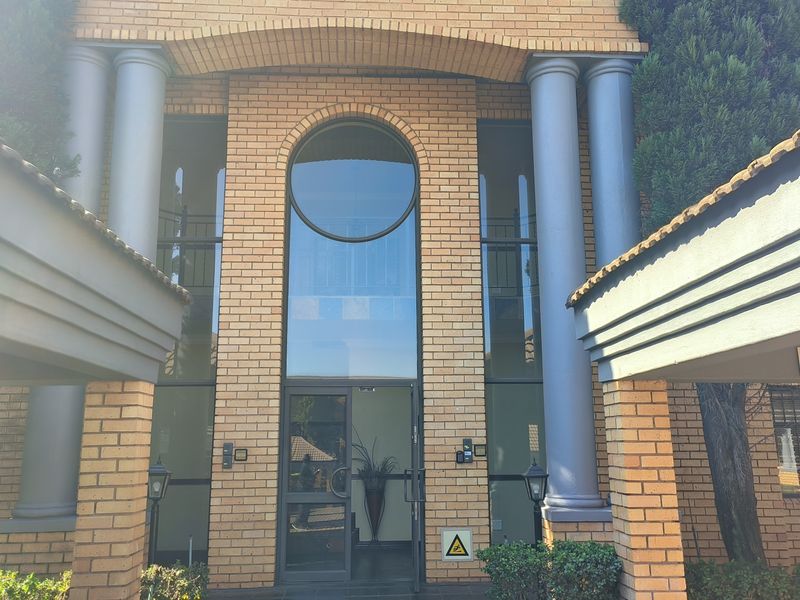 The front entrance of the office building features a prominent brick facade with decorative columns, a large arched window, and a glass-paneled entry door.