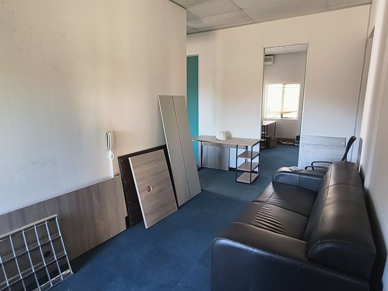 A functional office space featuring carpeted flooring, a suspended ceiling, and an integrated intercom system, currently requiring cosmetic updates to the walls and flooring.