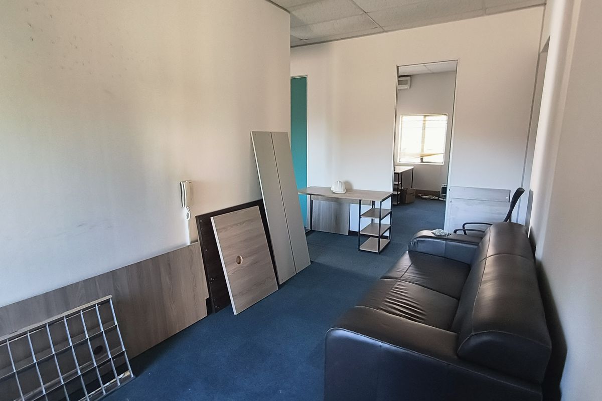 A functional office space featuring carpeted flooring, a suspended ceiling, and an integrated intercom system, currently requiring cosmetic updates to the walls and flooring.