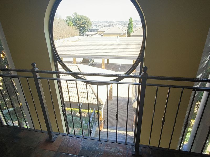 An interior view from an elevated landing featuring a distinctive circular window and a decorative wrought iron balustrade overlooking the property grounds.