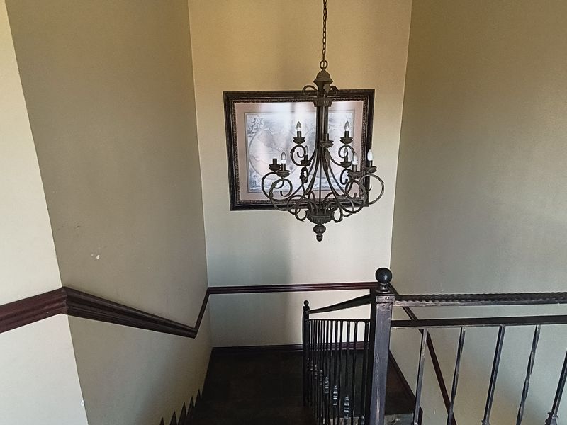 A staircase hallway featuring a decorative wrought iron chandelier, matching balustrade, and traditional chair rail molding.