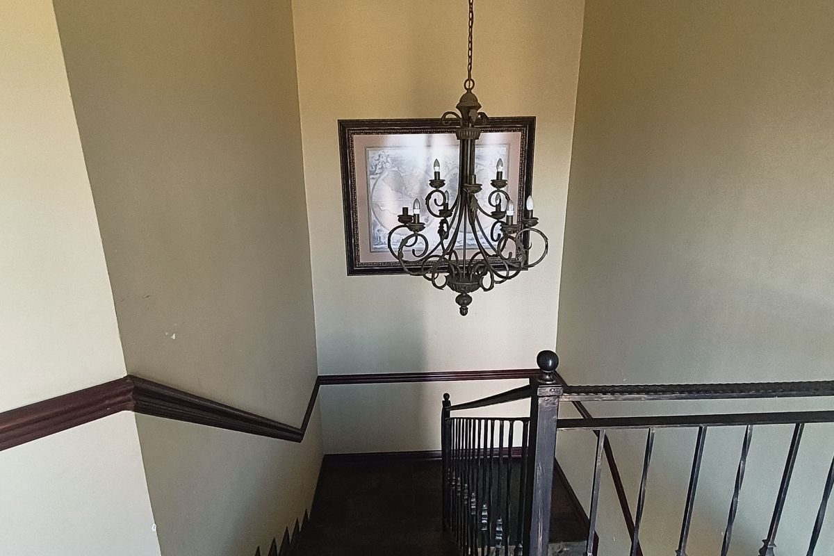A staircase hallway featuring a decorative wrought iron chandelier, matching balustrade, and traditional chair rail molding.