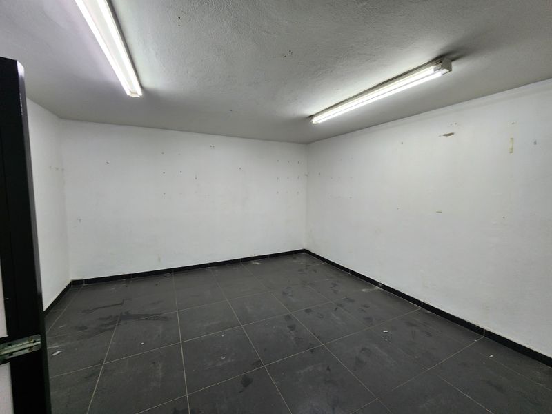 An empty utility space featuring tiled flooring and fluorescent strip lighting, suitable for storage or a functional workspace.