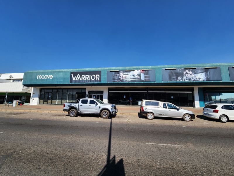 Front elevation of a retail property featuring large storefront signage, glass display windows, and a prominent metal awning along the street frontage.
