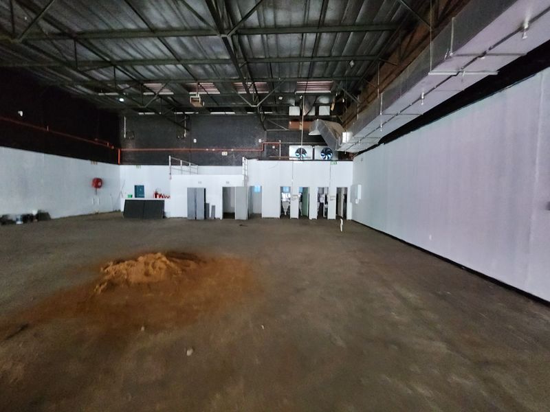 Large open-plan industrial utility space featuring exposed steel roof trusses, HVAC ducting, and multiple internal partitioned rooms, suitable for warehouse or commercial use.