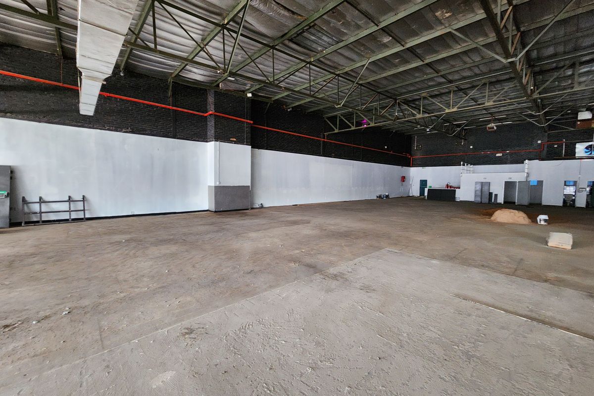 Spacious open-plan retail warehouse featuring high exposed ceilings, industrial steel trusses, and durable concrete flooring, suitable for various commercial or retail applications.