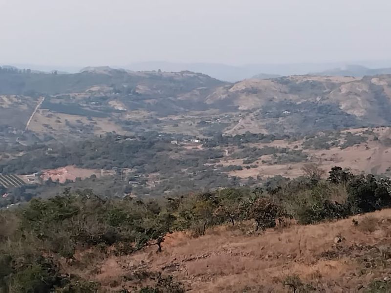 A wide-angle landscape view showcasing the rolling hills and natural terrain surrounding the small holding property.