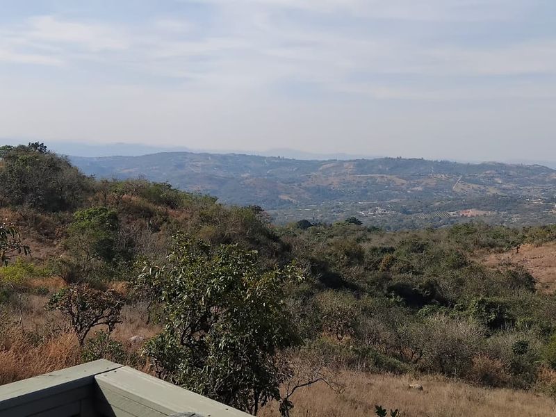 Expansive elevated landscape view overlooking the surrounding hills and natural vegetation of the small holding.