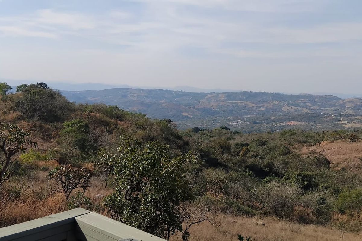 Expansive elevated landscape view overlooking the surrounding hills and natural vegetation of the small holding.
