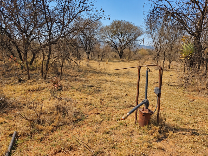 A view of the vacant land featuring a borehole pump installation set within a natural, dry landscape with scattered trees.