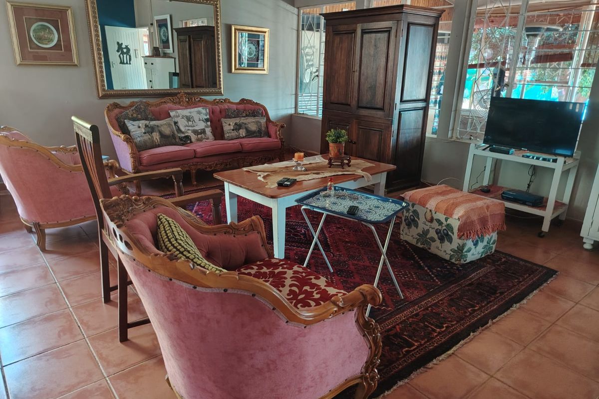 A spacious living room featuring tiled flooring and large windows with security bars, offering a bright and functional living space.