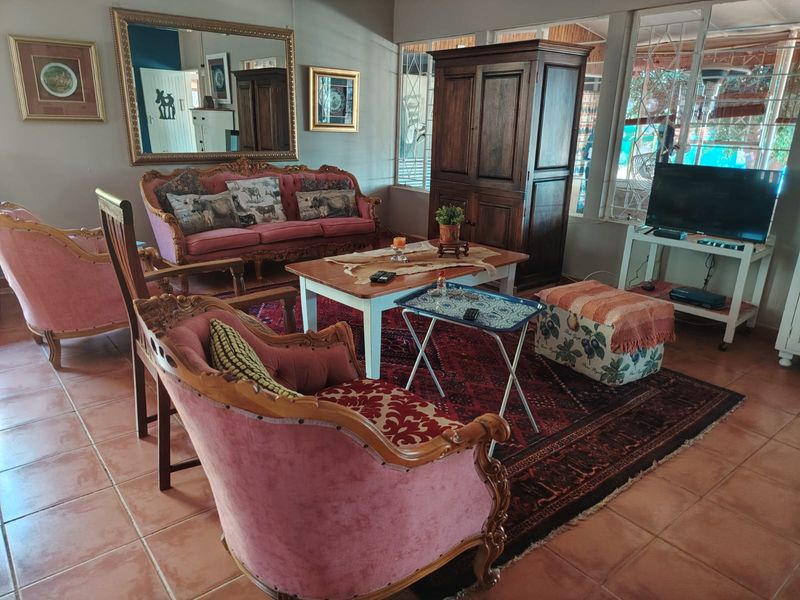 A spacious living room featuring tiled flooring and large windows with security bars, offering a bright and functional living space.