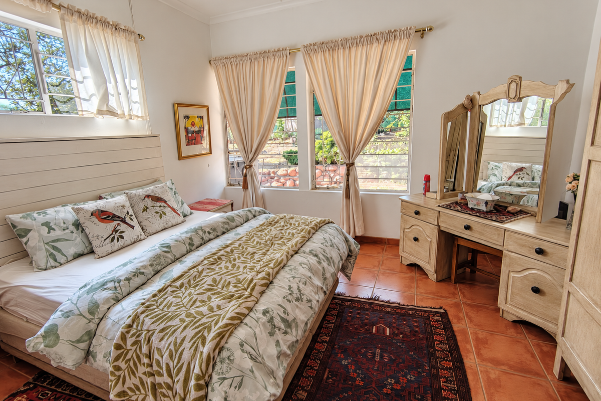A well-maintained bedroom featuring terracotta floor tiles, a built-in headboard, and large windows that provide ample natural light.