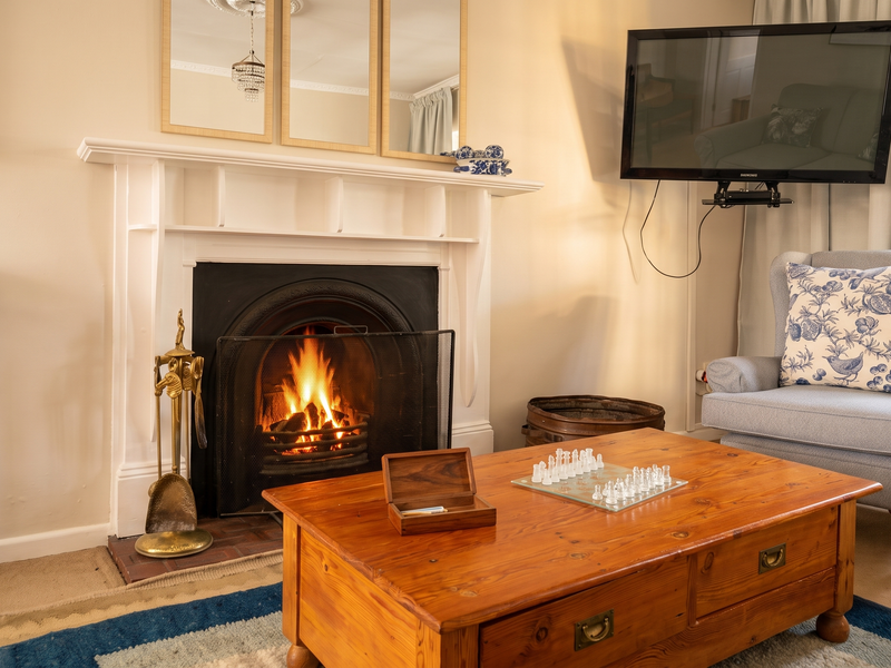 A cozy living room featuring a traditional fireplace with a white mantelpiece, decorative crown molding, and a ceiling rose.