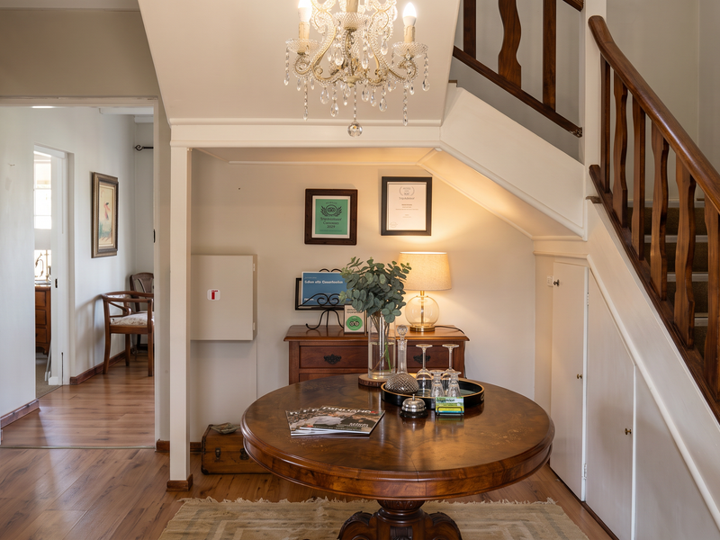 Welcoming entrance hall featuring a classic wooden staircase with integrated under-stair storage, elegant chandelier lighting, and warm laminate flooring.