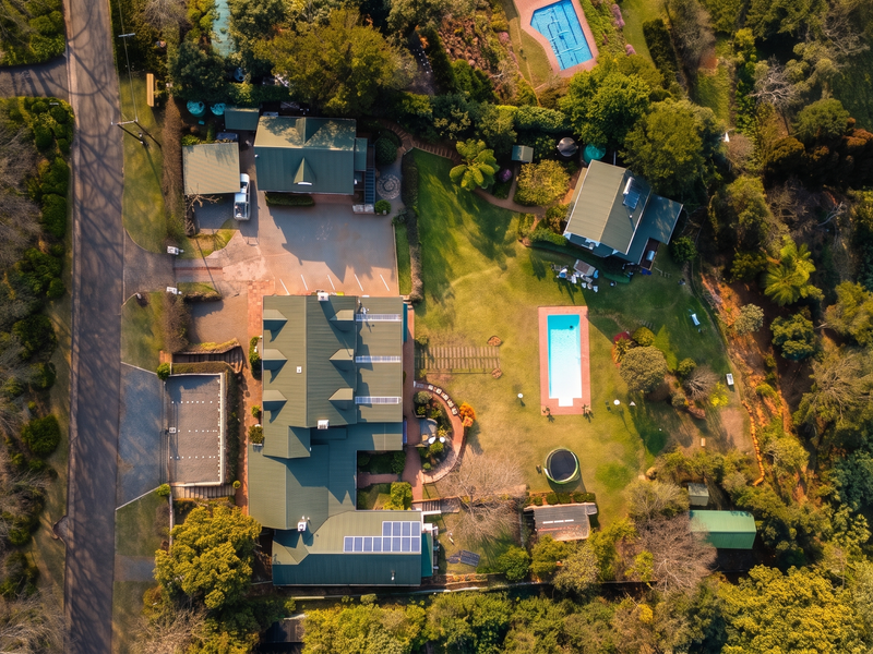 Aerial view of the guest house property featuring multiple buildings, a swimming pool, solar panels, and extensive landscaped grounds.